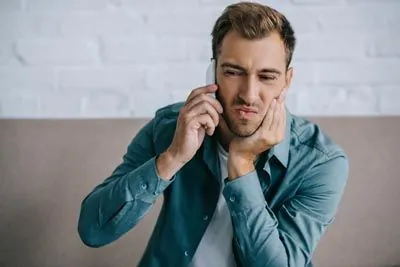 man holding his mouth from tooth pain scheduling an emergency dental appointment