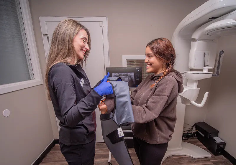 Team member fitting patient with X-ray apron